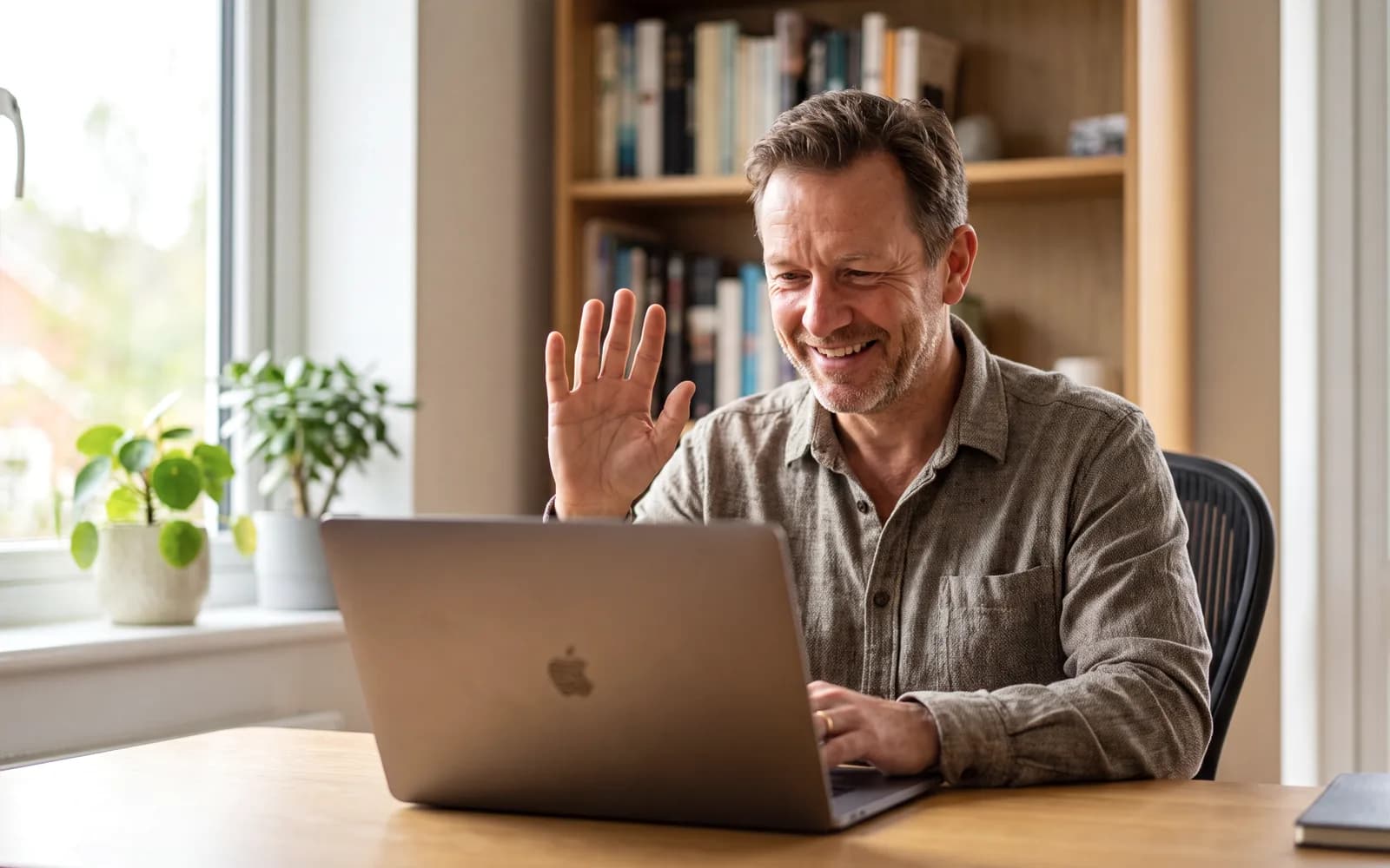 Man waving at a laptop during a video call