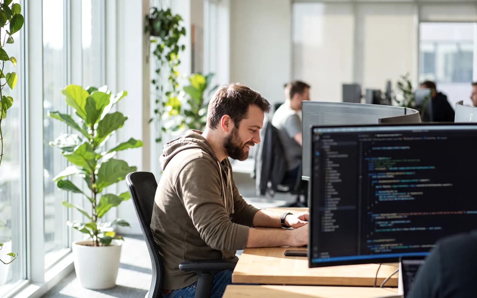 A developer working at a desk with dual monitors